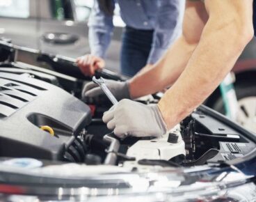 Free Photo _ A man mechanic and woman customer look at the car hood and discuss repairs